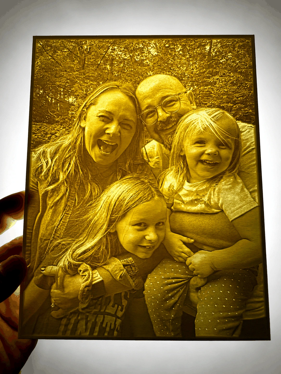 A hand holding an illuminated custom family lithophane.